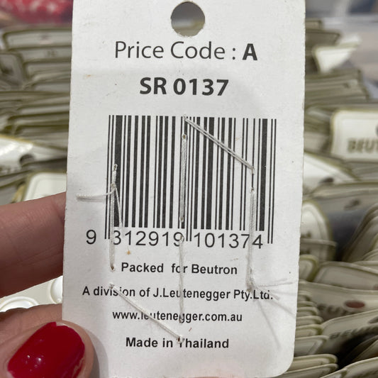 Close-up of a product tag with a barcode and text, held by a hand with red nail polish.