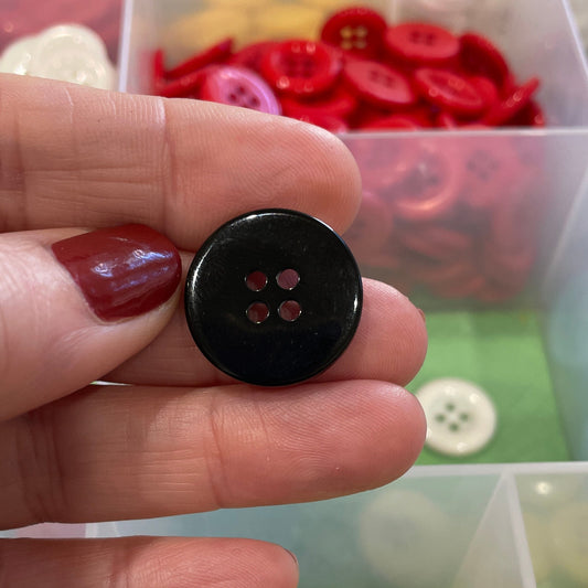 Hand holding a black button with colorful buttons in the background