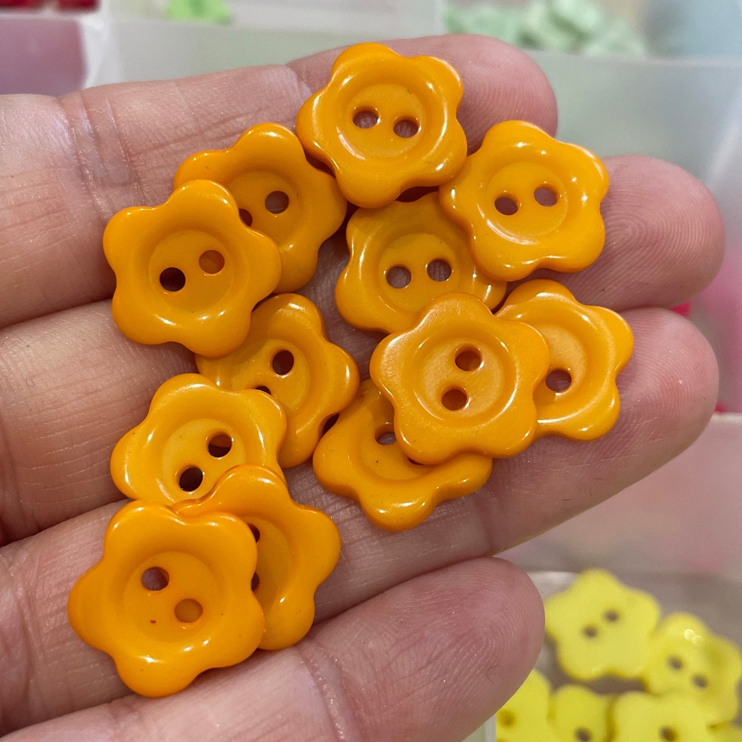 Hand holding yellow flower-shaped buttons with a blurred background