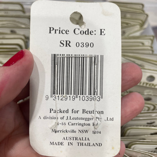 Close-up of a price tag held by a hand with red nail polish, blurred background