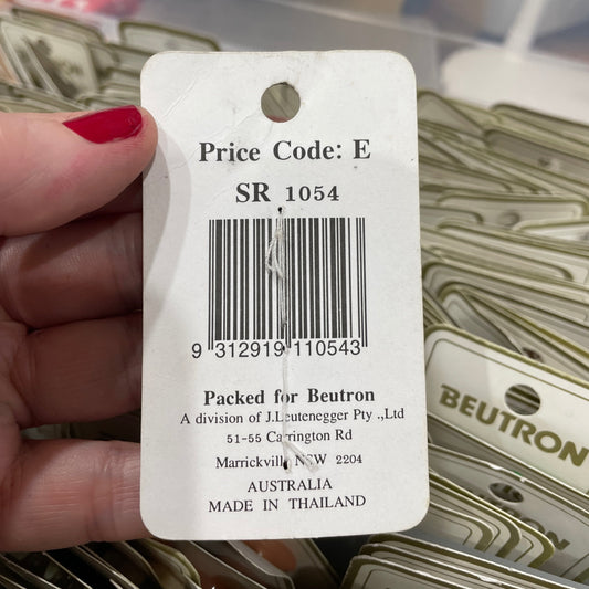 Close-up of a price tag with a barcode held by a hand, with BEUTRON products in the background.