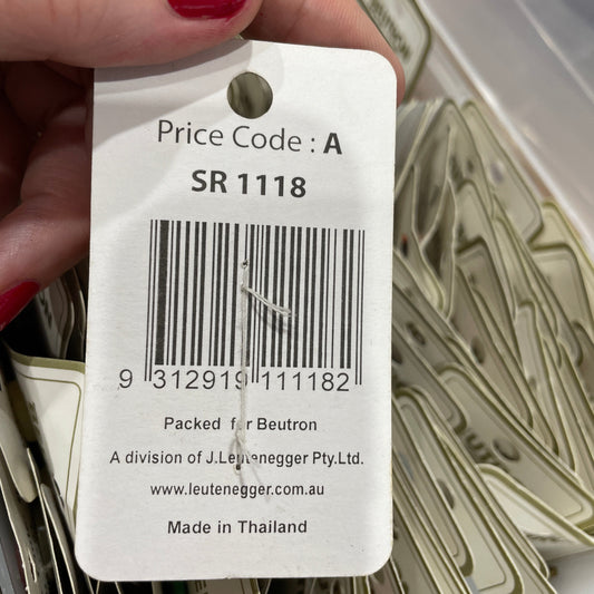 Hand holding a price tag with a barcode and text, surrounded by more price tags.