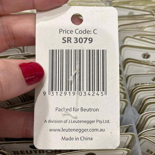 Hand holding a product tag with barcode and text, with a background of similar tags.