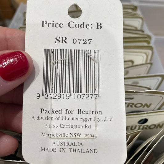 Close-up of a product tag with a barcode and text, held by a hand with red nail polish.