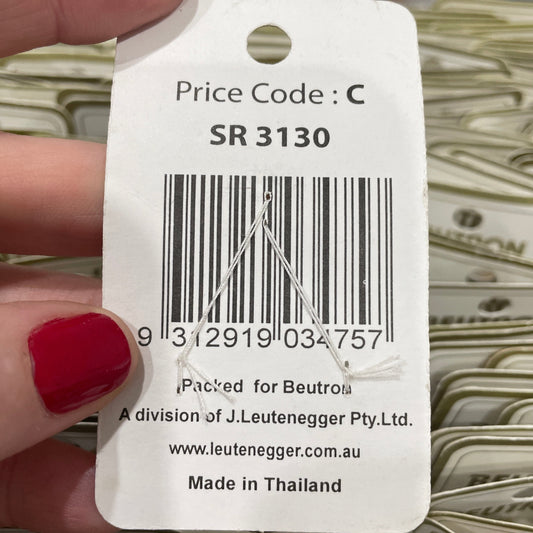 Close-up of a product tag with a barcode and text, held by a hand with red nail polish.