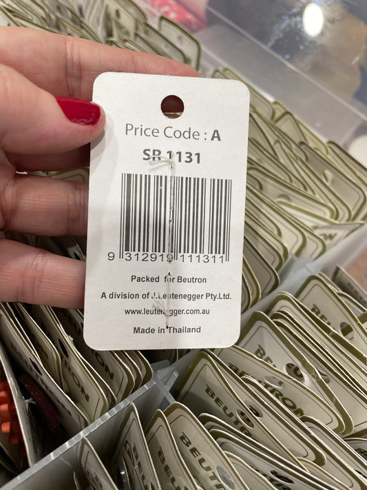 Hand holding a price tag with a barcode and text, surrounded by similar tags.