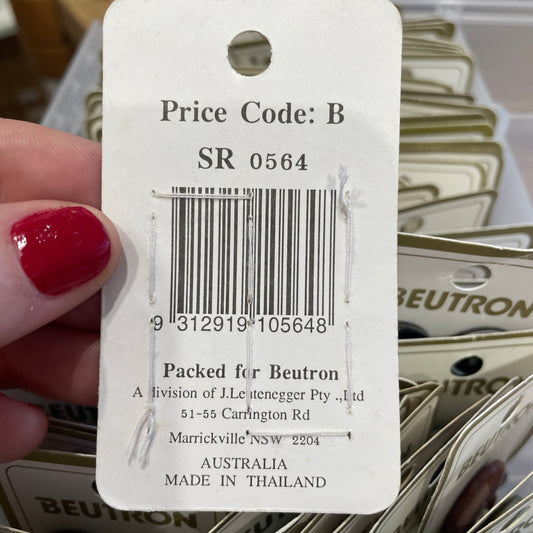 Close-up of a price tag with a barcode held by a hand with red nail polish, with a background of similar tags.