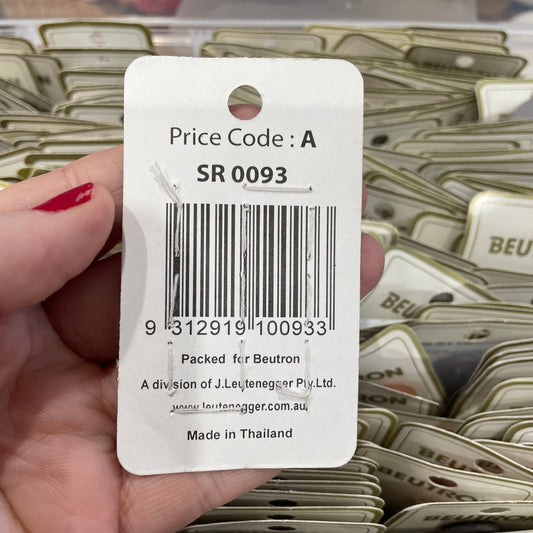 Close-up of a price tag with a barcode held by a hand, with product packaging in the background.