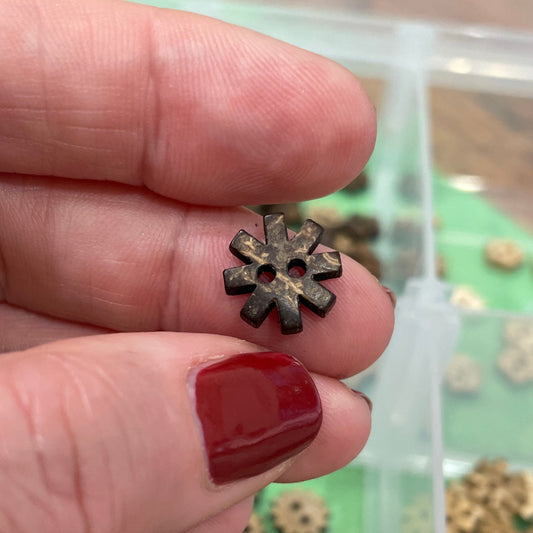 Hand holding a small flower-shaped button with buttons in the background