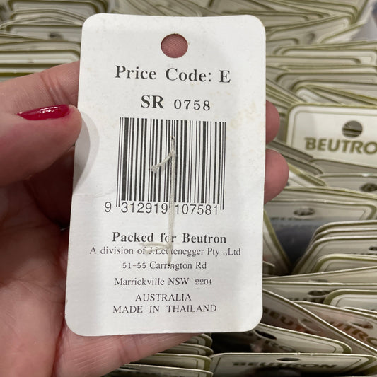Close-up of a product tag with a barcode and text, held by a hand.