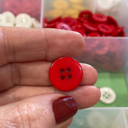 Hand holding a red button with a background of various buttons in containers