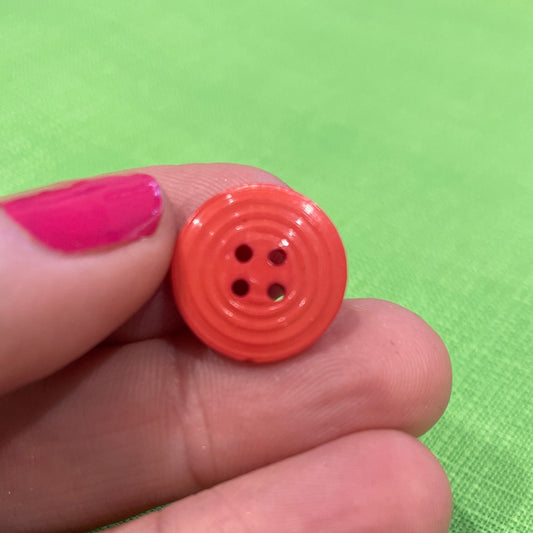 Red button held between fingers against a green background
