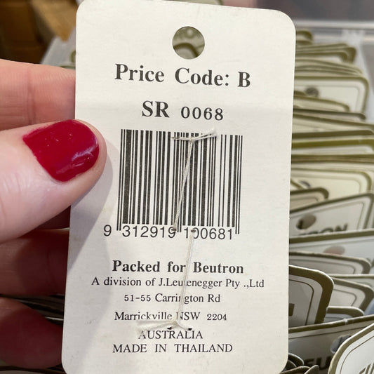 Close-up of a price tag with a barcode held by a hand, with more tags in the background.