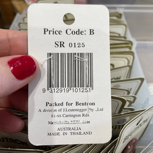 Close-up of a product tag with a barcode and text, held by a hand with red nail polish.