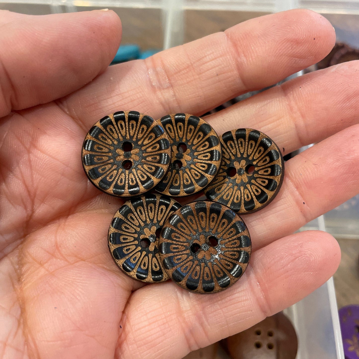 Hand holding decorative buttons with a blurred background of more buttons.