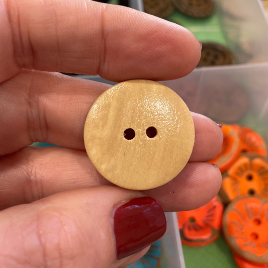 Hand holding a yellow button with a colorful array of buttons in the background
