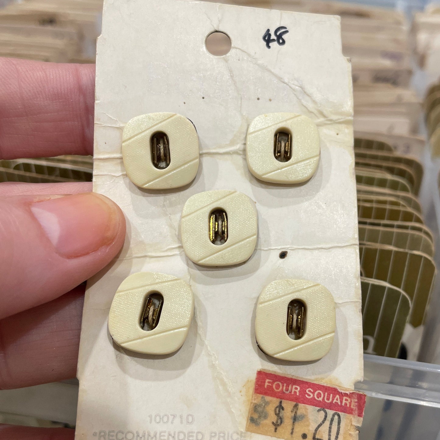 Set of beige buttons on a card held by a hand with a blurred background