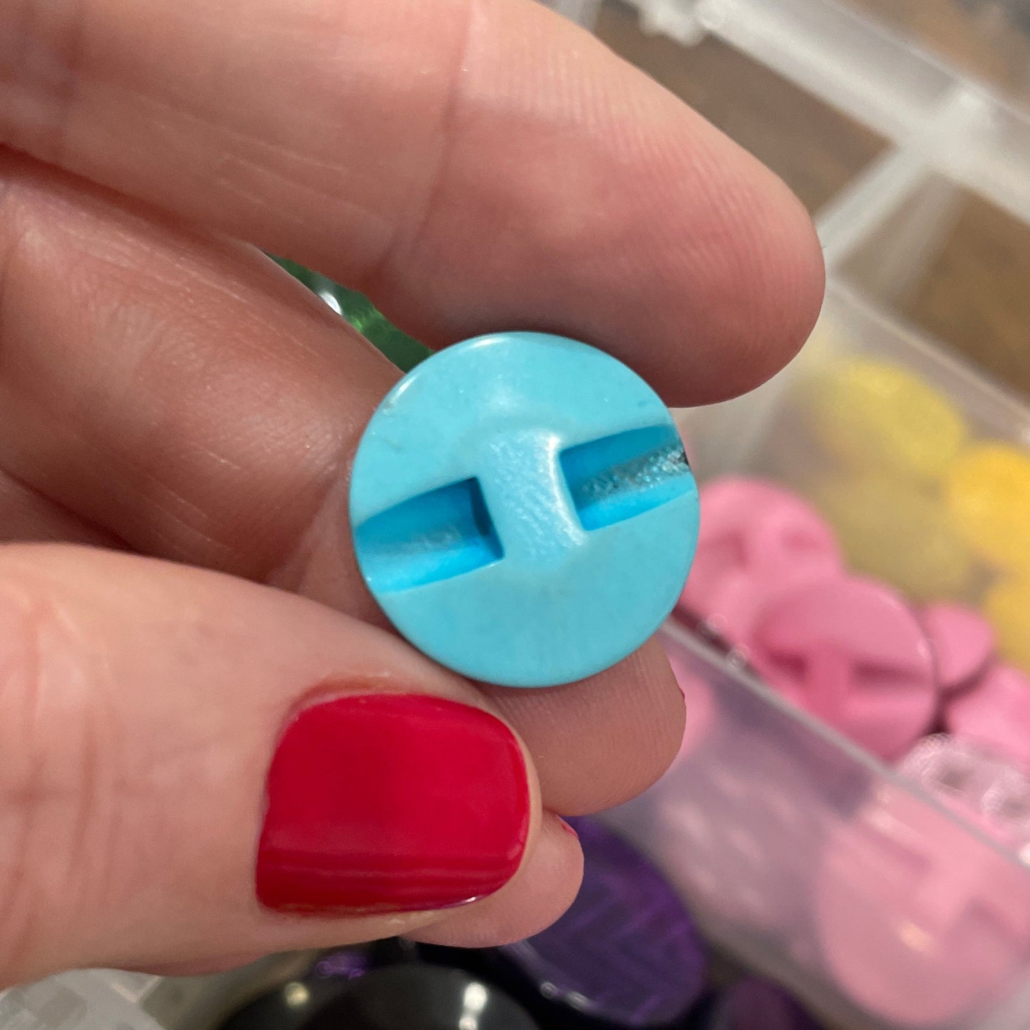 Hand holding a blue plastic letter 'H' with colorful plastic letters in the background.