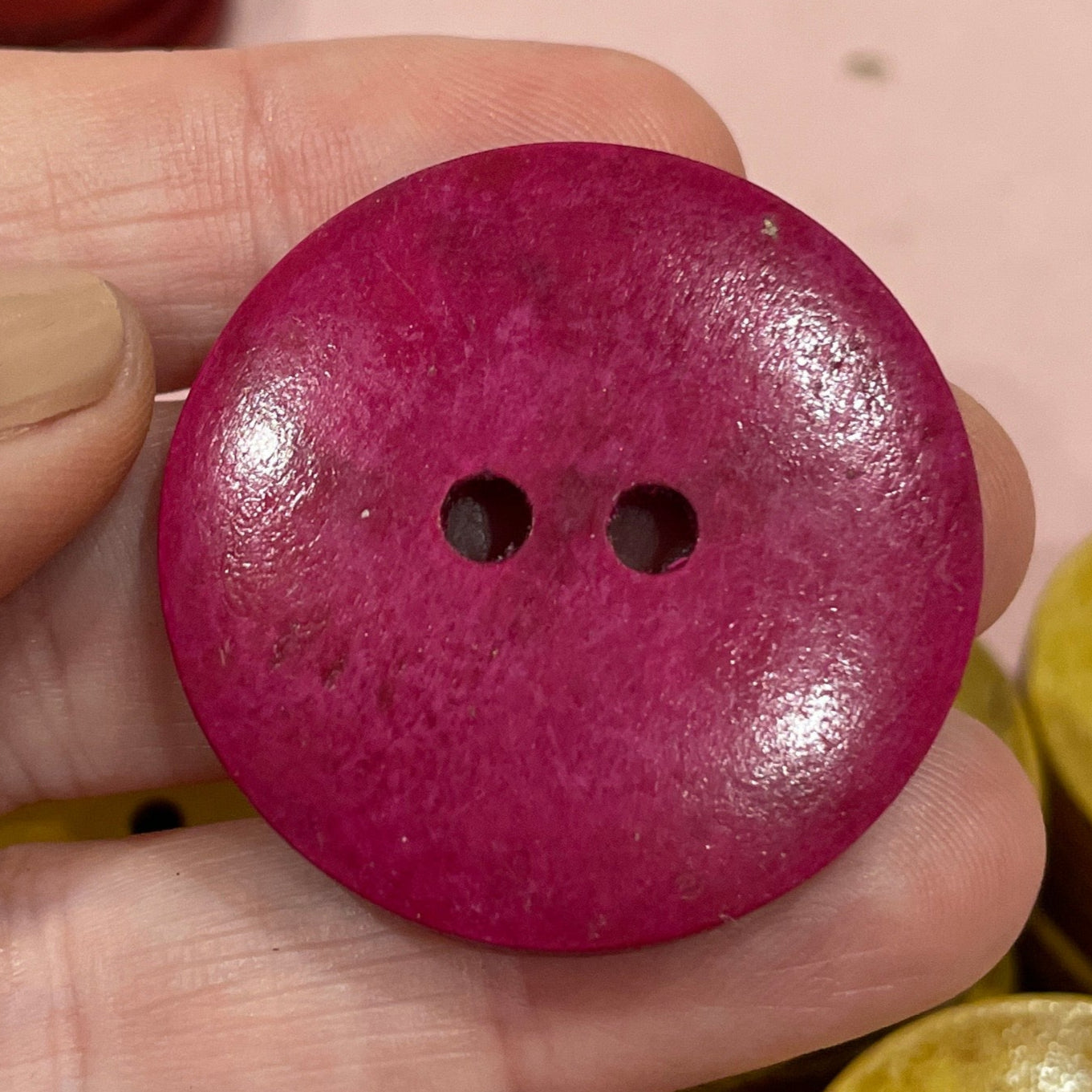 Hand holding a purple button with colorful buttons in the background