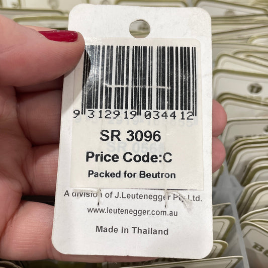 Hand holding a product tag with a barcode and text, surrounded by more tags.
