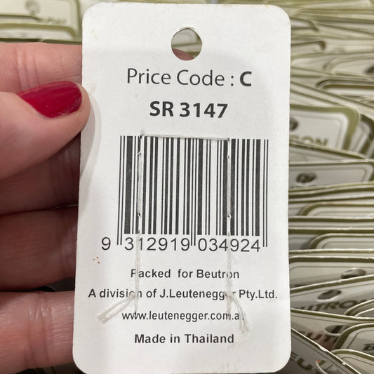 Close-up of a product tag with a barcode and text, held by a hand.