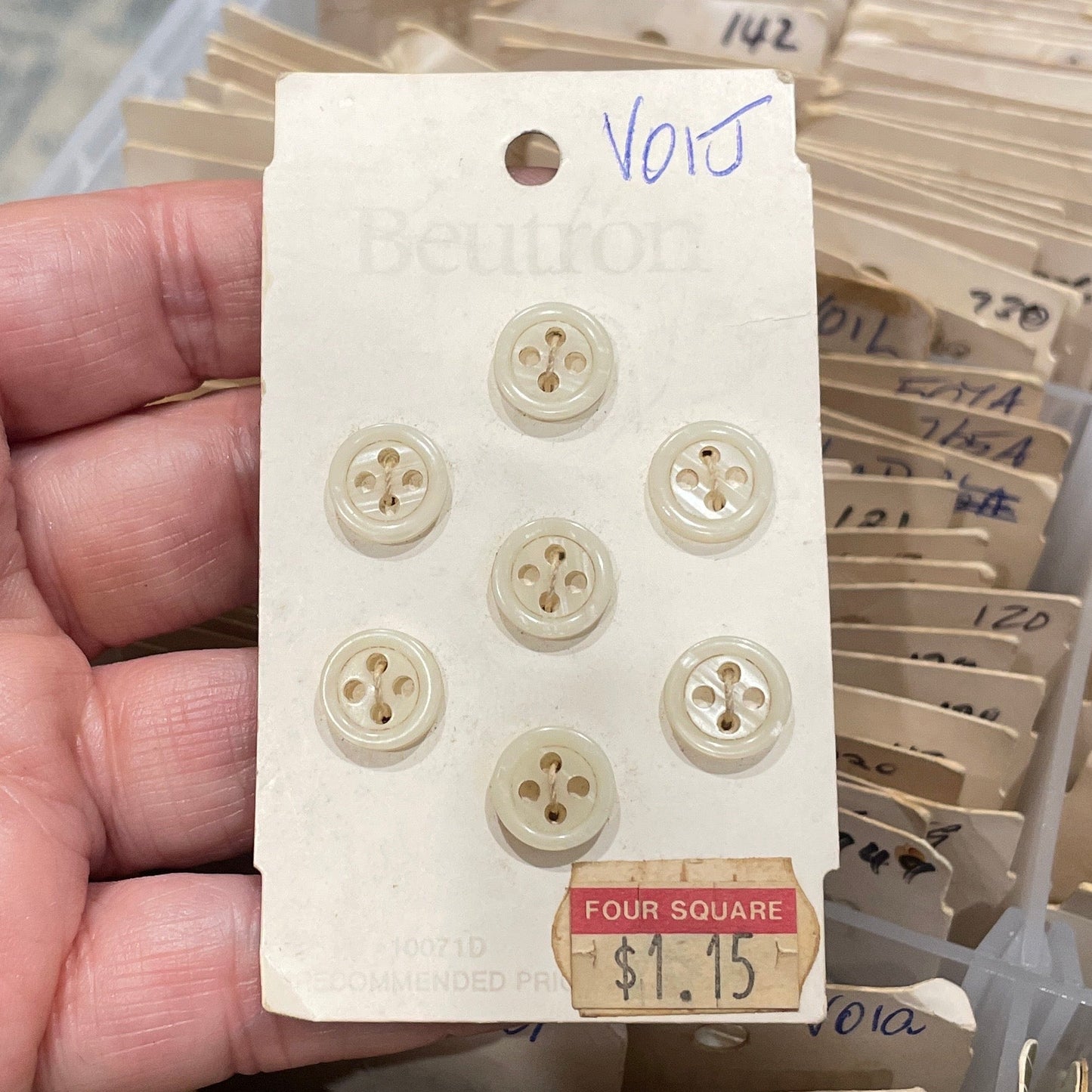 Hand holding a card with buttons in front of a collection of similar cards.