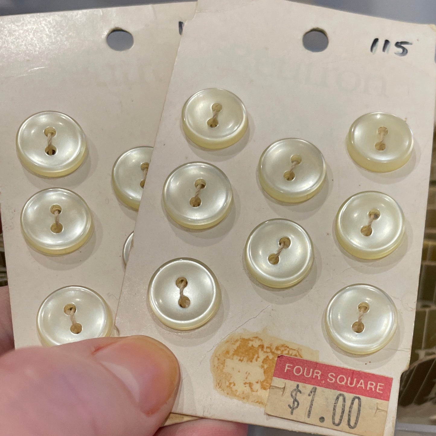 Hand holding a card with white buttons and a price tag, with a blurred background.