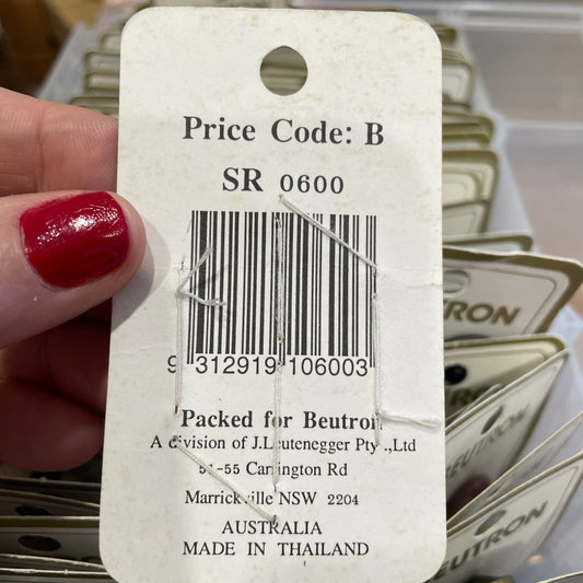 Close-up of a product tag with a barcode, held by a hand with red nail polish.