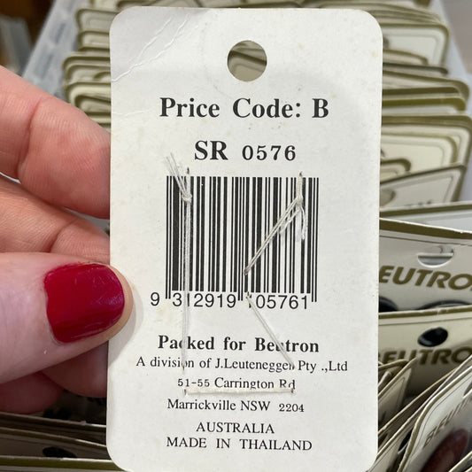 Close-up of a hand holding a Butron price tag with a barcode, surrounded by more price tags.