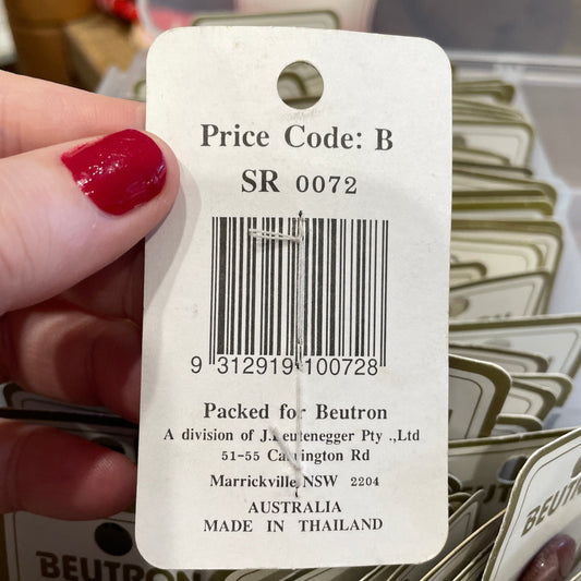 Close-up of a price tag held by a hand with red nail polish, surrounded by more tags.