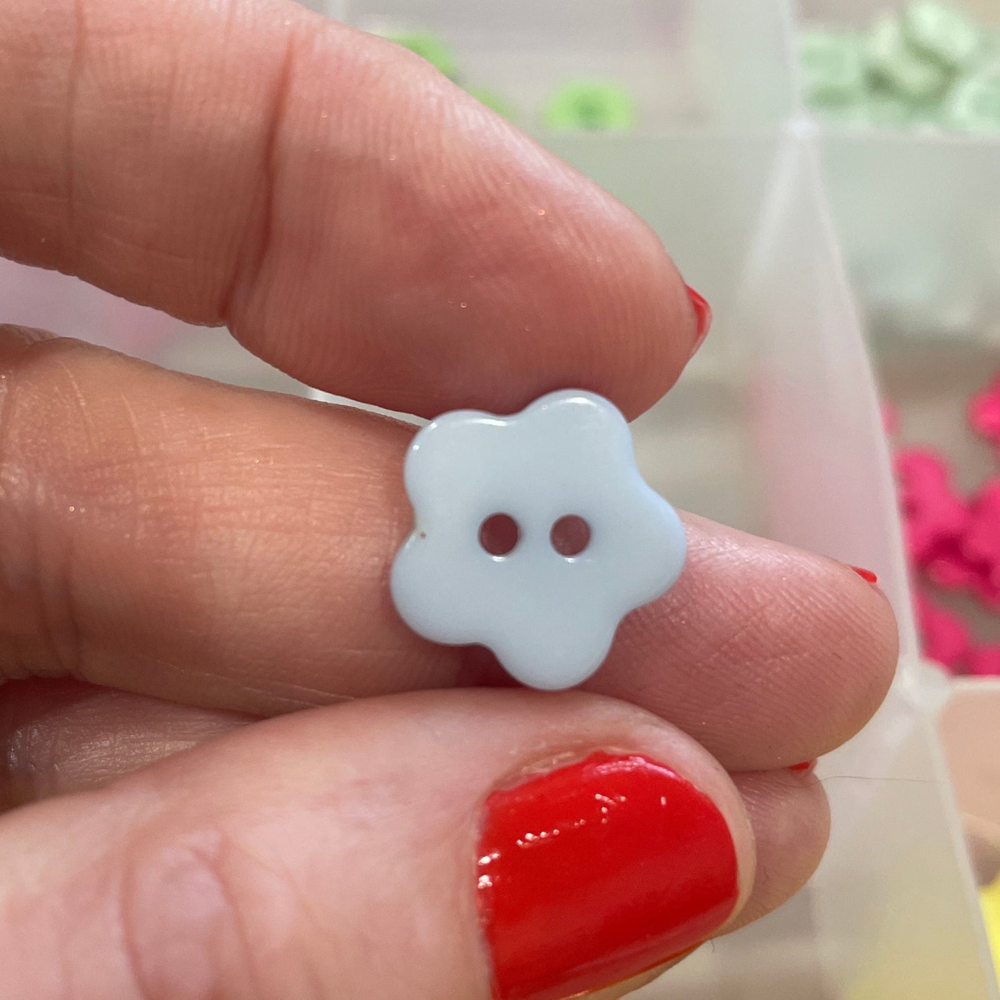 White flower-shaped button held between fingers with a colorful background