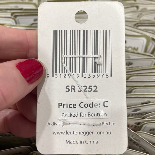Close-up of a price tag with a barcode and text, held by a hand.
