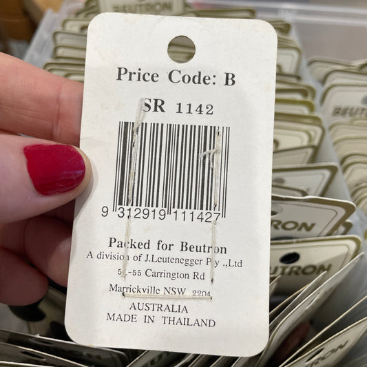 Close-up of a price tag with a barcode and text, held by a hand with red nail polish.