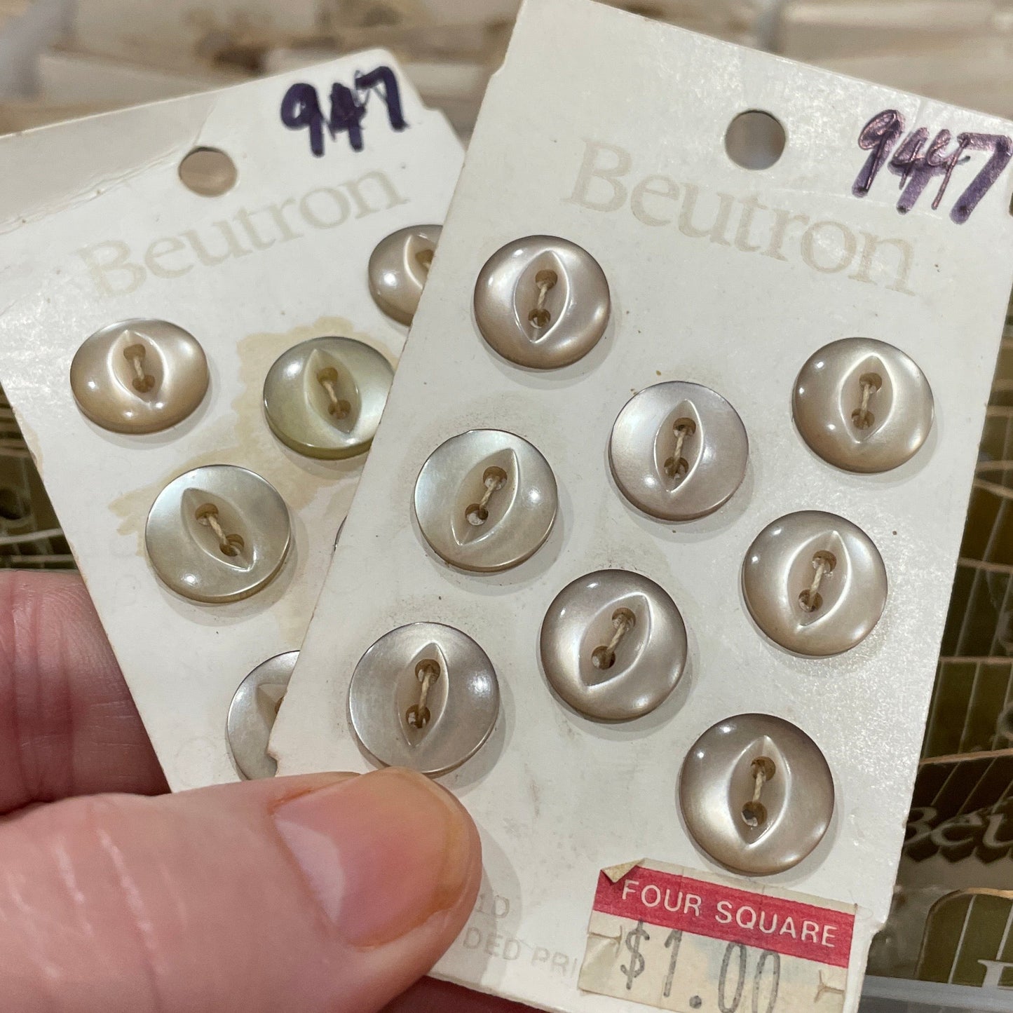 Packaging of buttons with a visible brand label held by a hand.