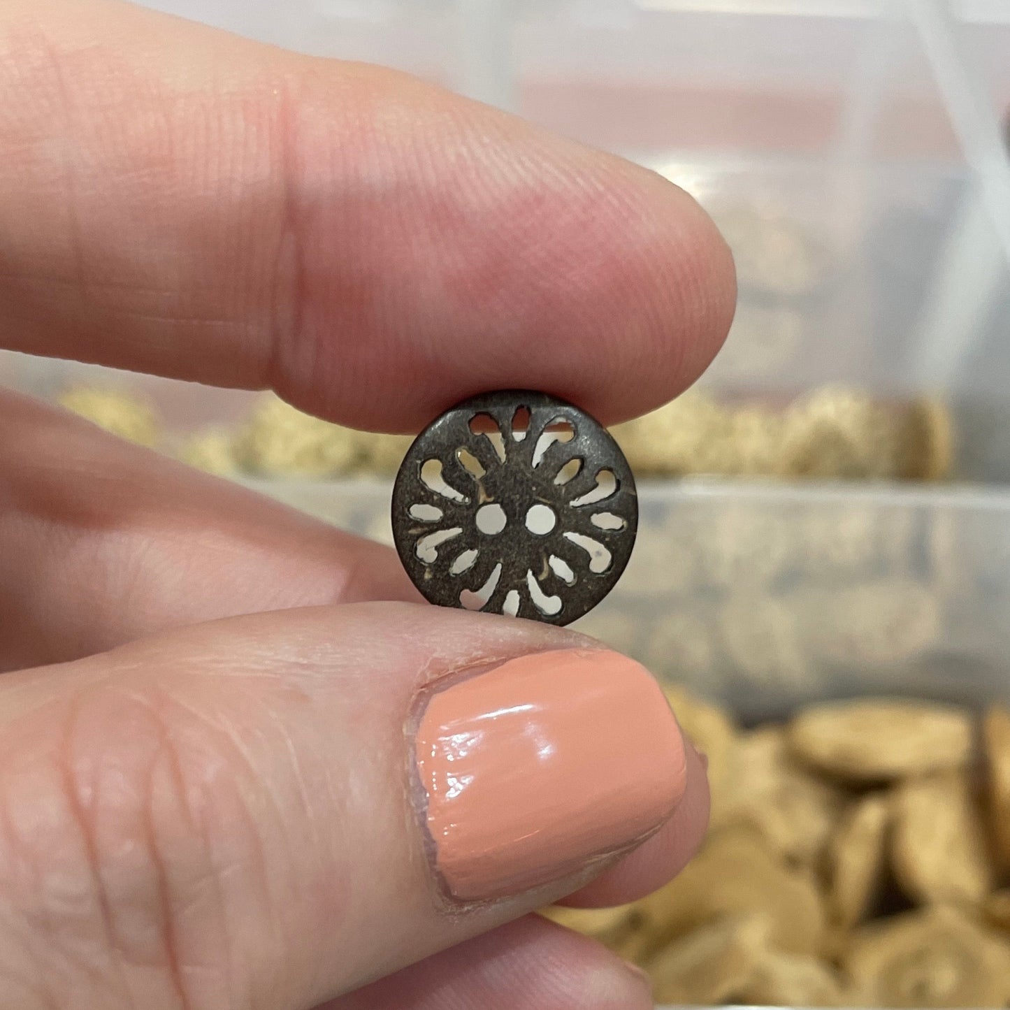Hand holding a decorative button with a blurred background of button collection