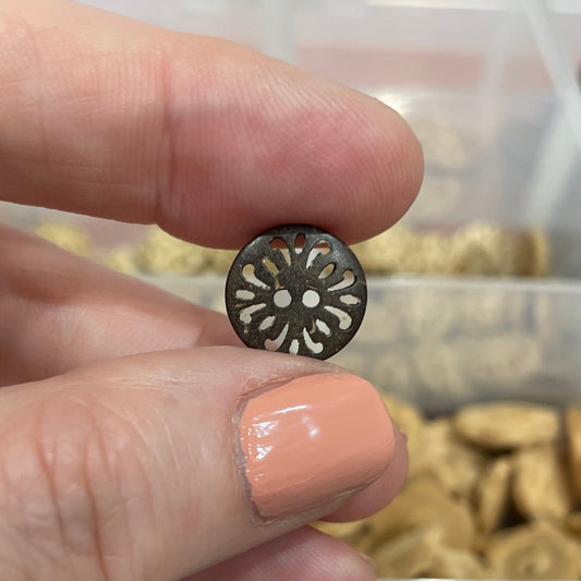 Hand holding a decorative button with a blurred background of button collection