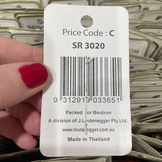 Hand holding a price tag with a barcode and text, against a patterned background.
