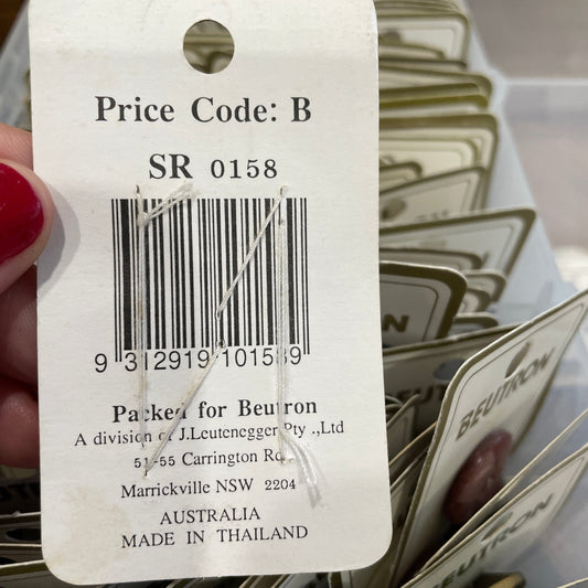 Close-up of a tag with a barcode and text, held by a hand.