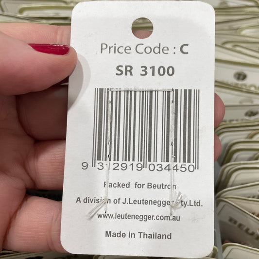 Close-up of a price tag with a barcode held by a hand, surrounded by similar tags.