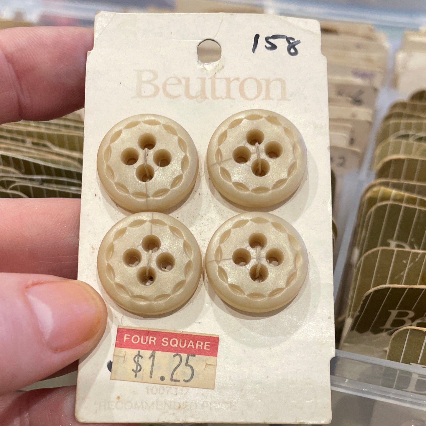 Set of four buttons on a card held by a hand with a blurred background
