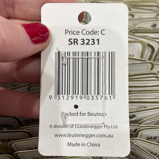Close-up of a product tag with a barcode held by a hand, with multiple tags in the background.
