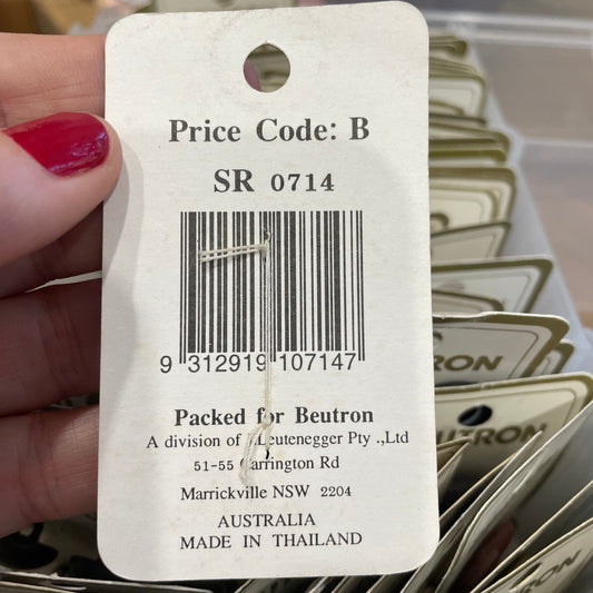 Close-up of a price tag with a barcode and text, held by a hand.