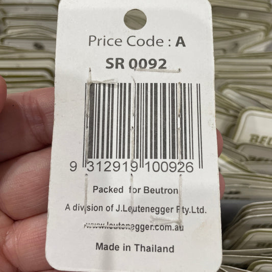 Close-up of a product tag with a barcode held by a hand, with a blurred background.