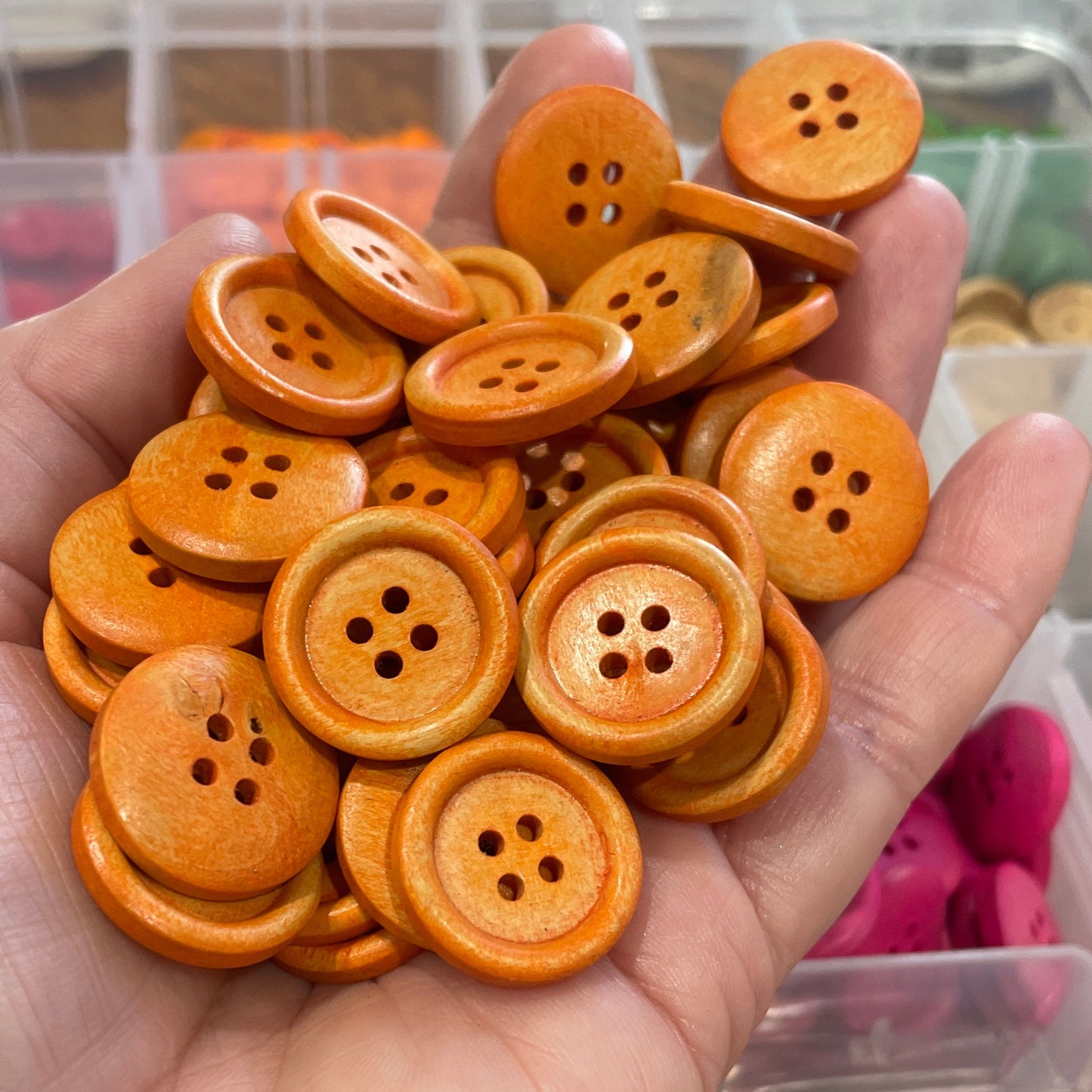 Hand holding a collection of orange buttons with a blurred background