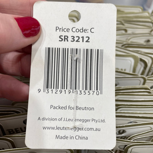 Hand holding a product tag with a barcode and text, with multiple tags in the background.