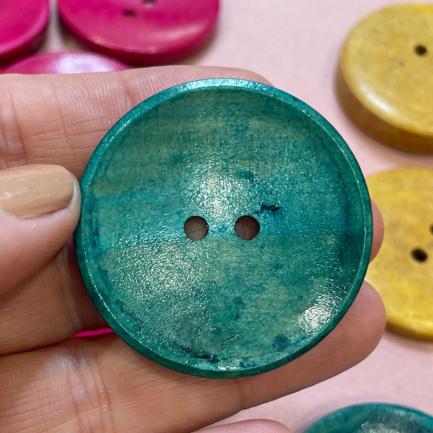 Hand holding a green button with colorful buttons in the background