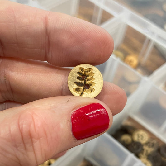 Button held between fingers with a container of buttons in the background