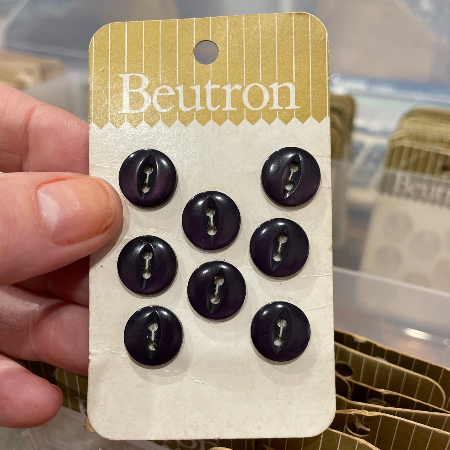 Pack of black buttons held by a hand with a blurred background
