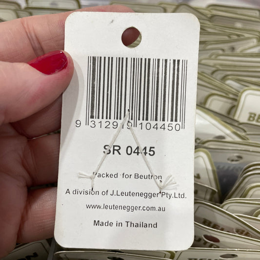 Close-up of a product tag held by a hand with red nail polish, with blurred background