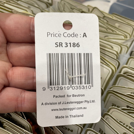 Close-up of a price tag with a barcode held by a hand, surrounded by similar tags.